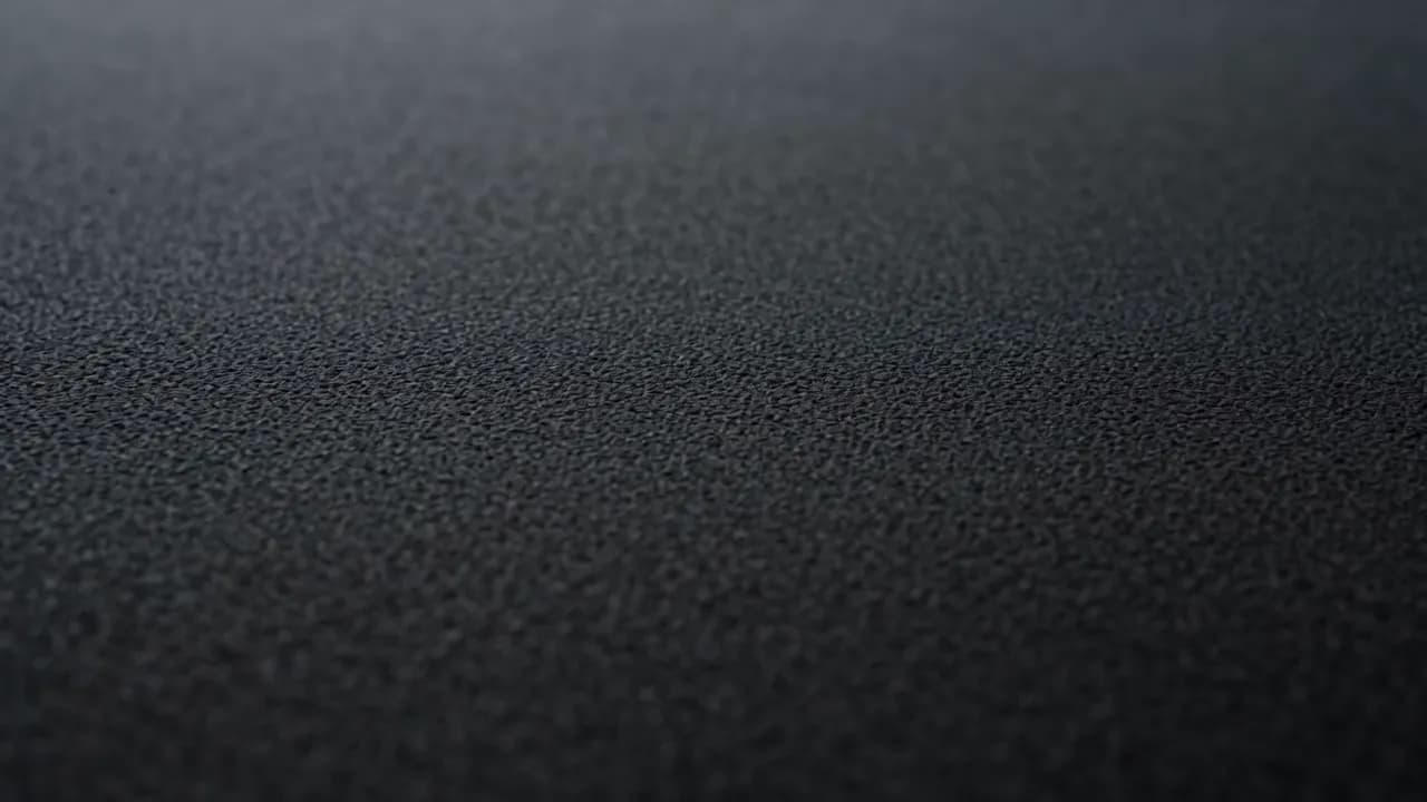 Slow close-ups of charcoal stone, brushed steel, dark timber, and water catching a thin line of light.